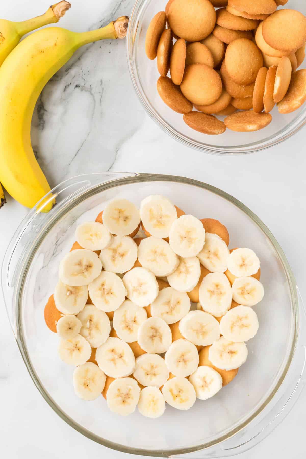 Slices of banana placed over the layer of vanilla wafers in the bowl.