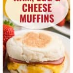Close-up of a ham, egg, and cheese muffin sandwich on a plate with strawberries and orange juice.