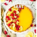 Top-down view of a lemon raspberry tart garnished with raspberries and lemon slices, surrounded by fresh fruit.