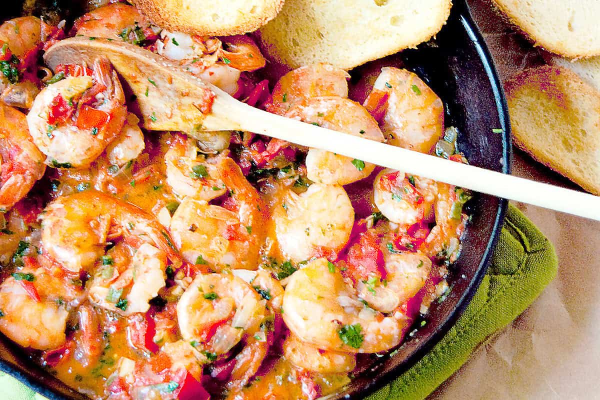 A black iron skillet filled with cooked cilantro shrimp.