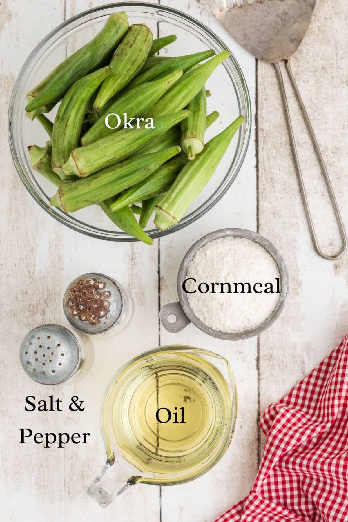 Ingredients for fried okra on a wooden surface in separate containers.