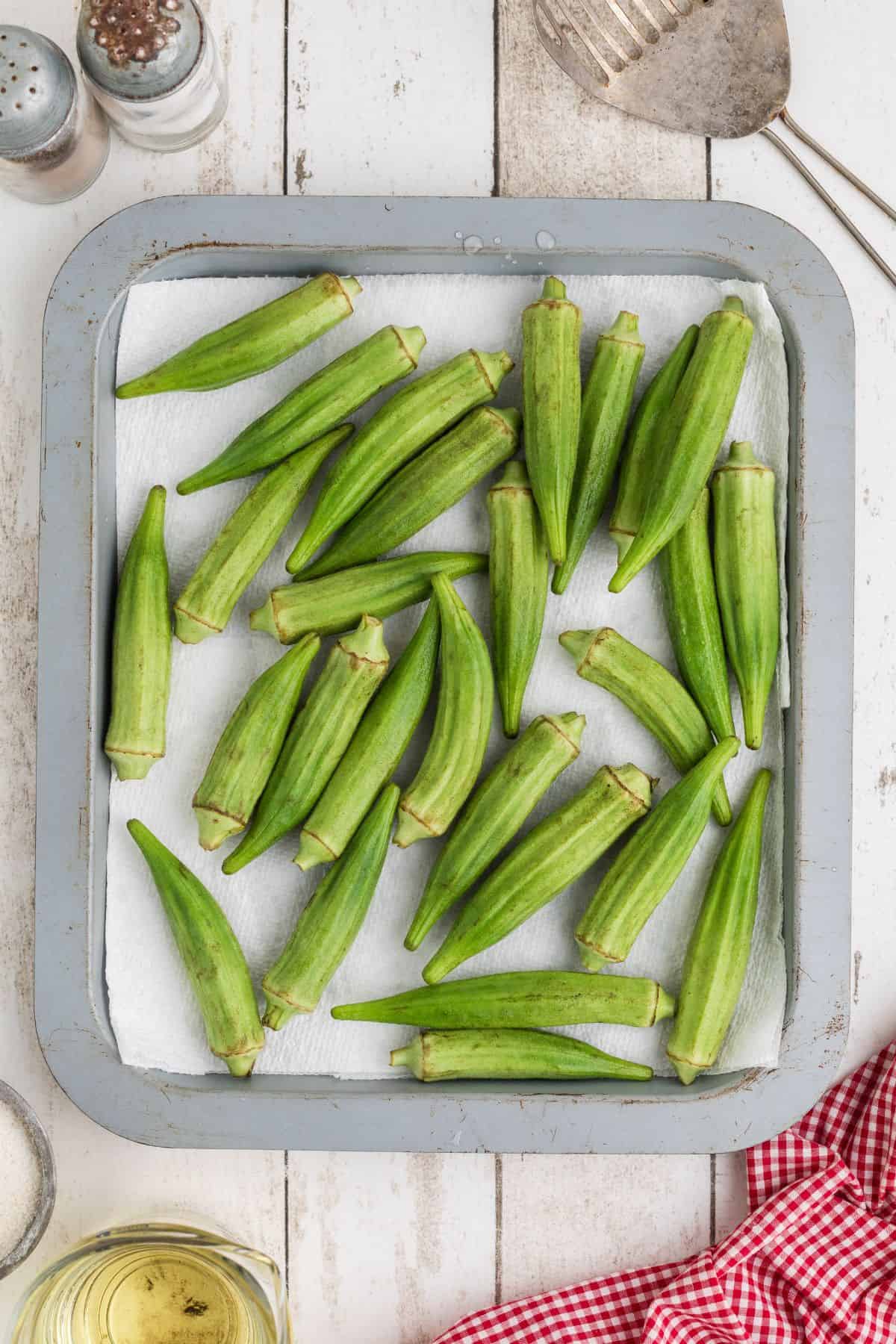 Washed okra drying on a paper towel lined pan.