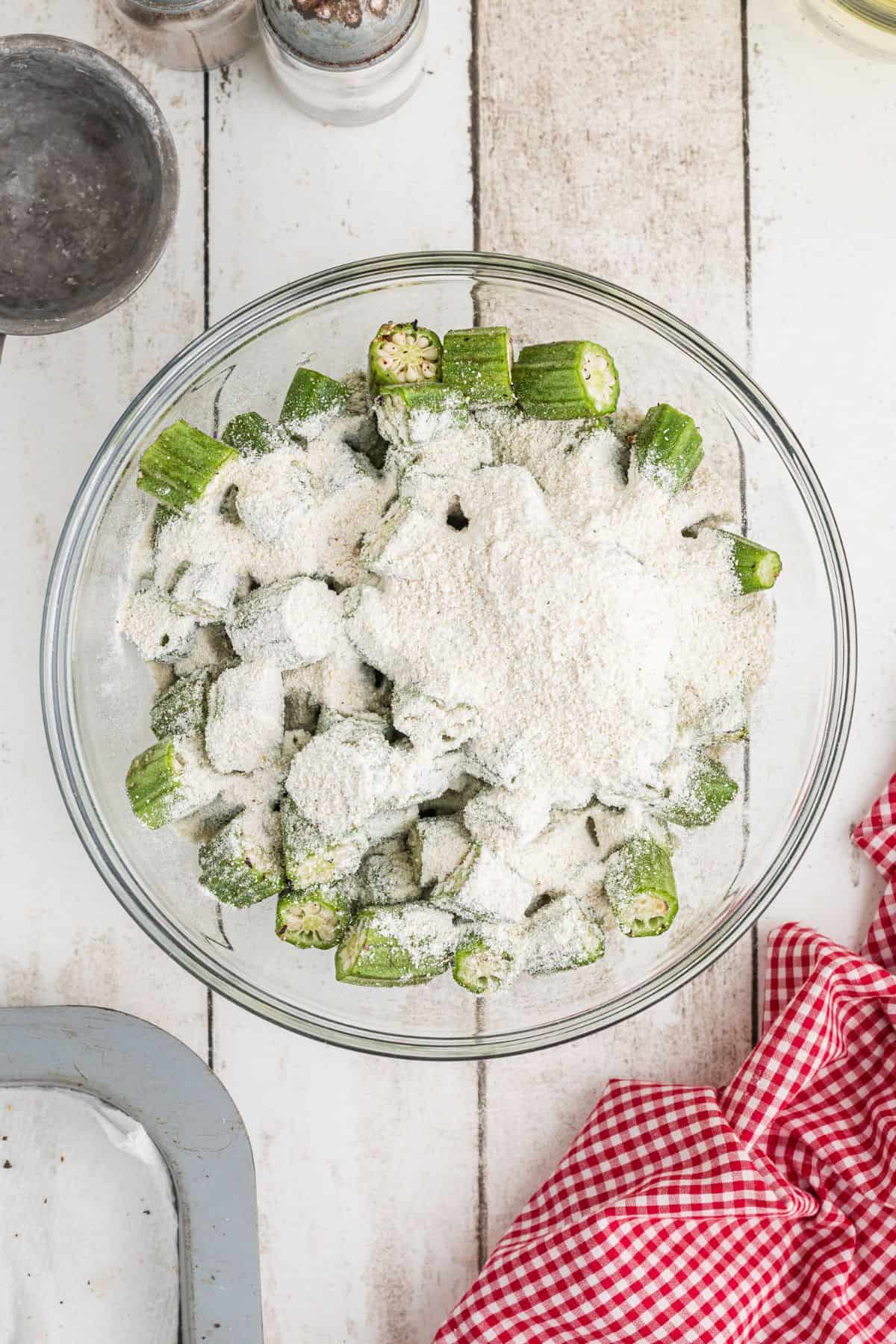 Okra and cornmeal in a mixing bowl.
