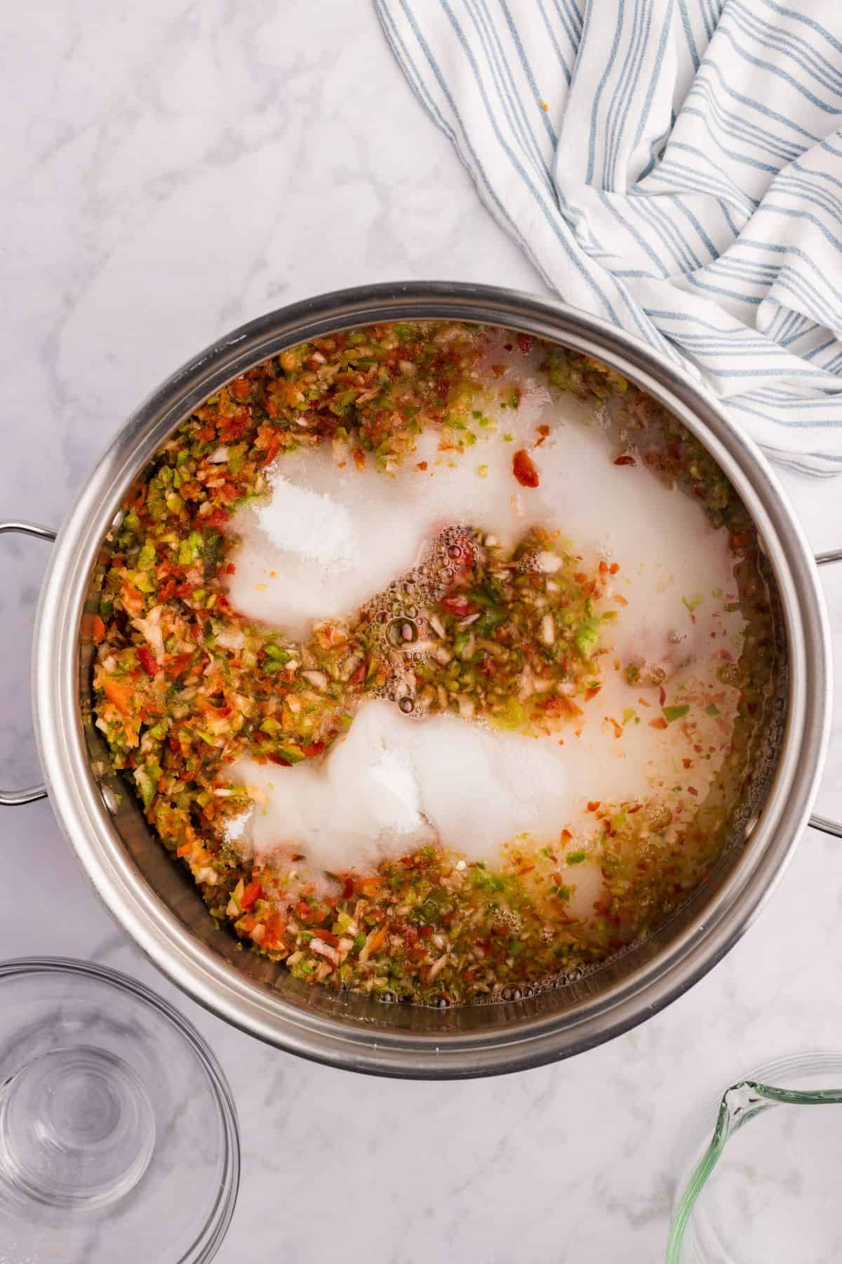 Chopped peppers, onions, and sugar in a saucepan.