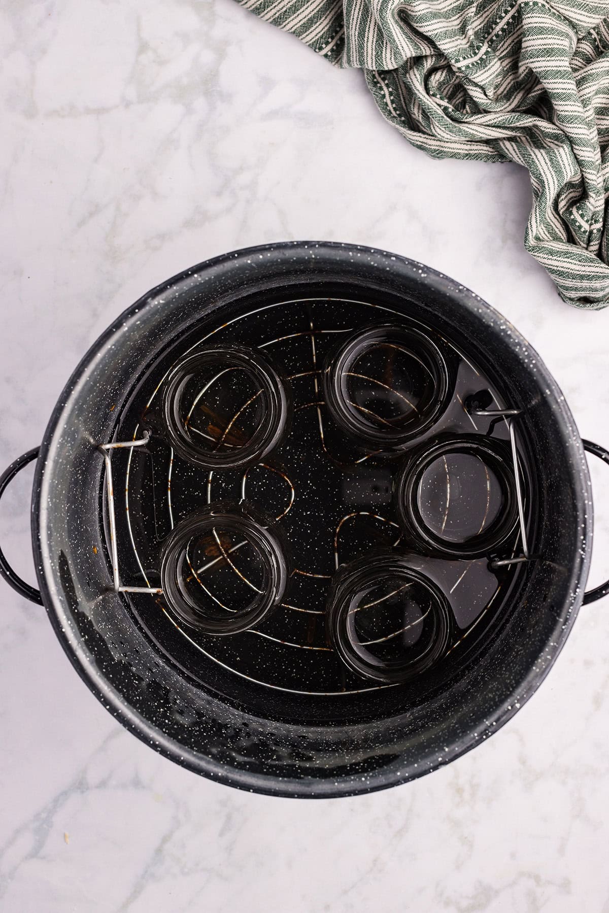 A boiling water bath canner 2/3 full with water and canning jars.