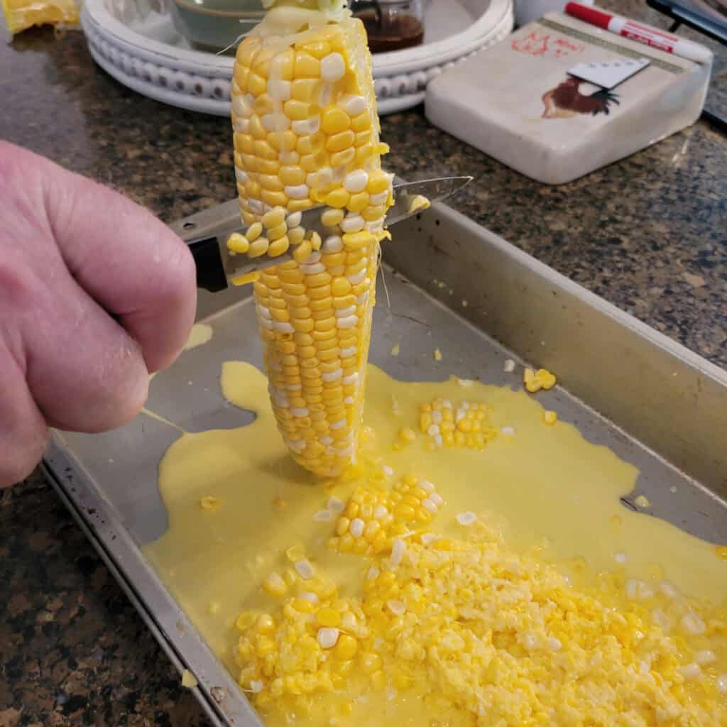 Cutting tips of kernels off a corn cob.
