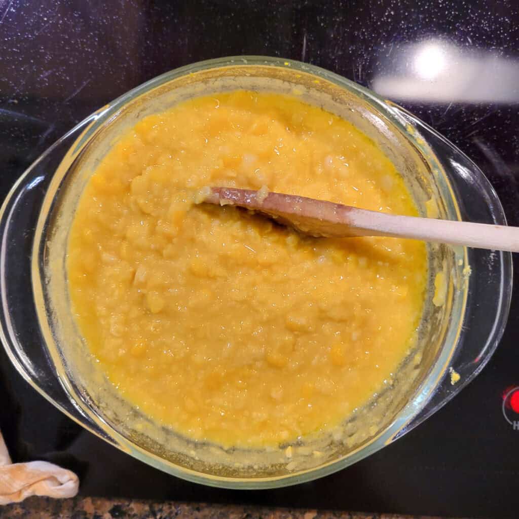 Stirring the corn with a wooden spoon.