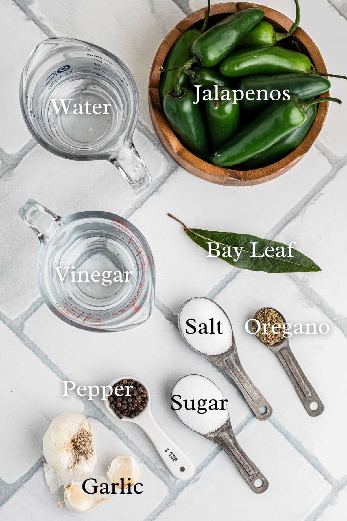 Ingredients for pickled jalapenos in separate containers on a tile background.