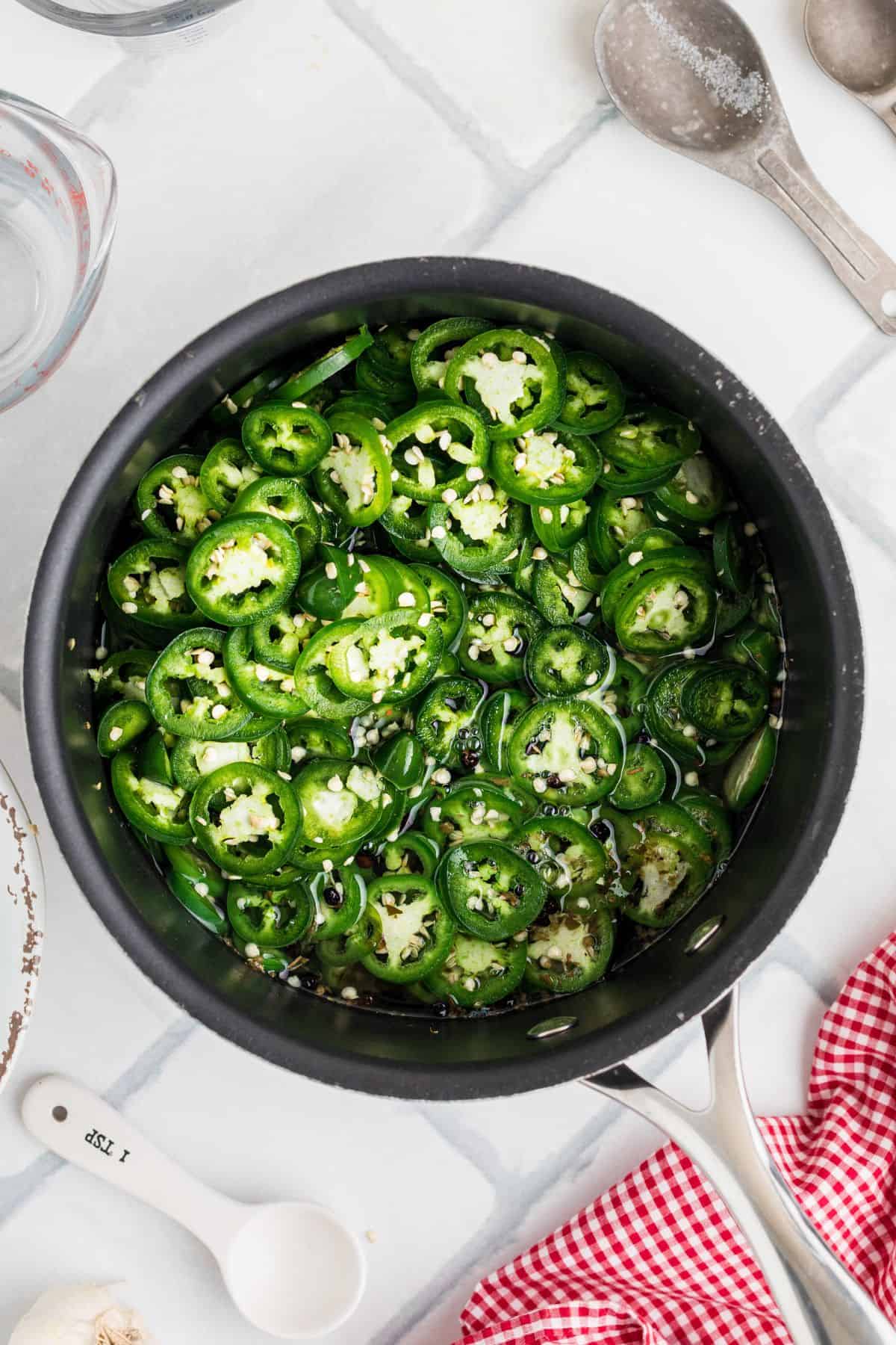 Jalapenos added to the brine in the saucepan.