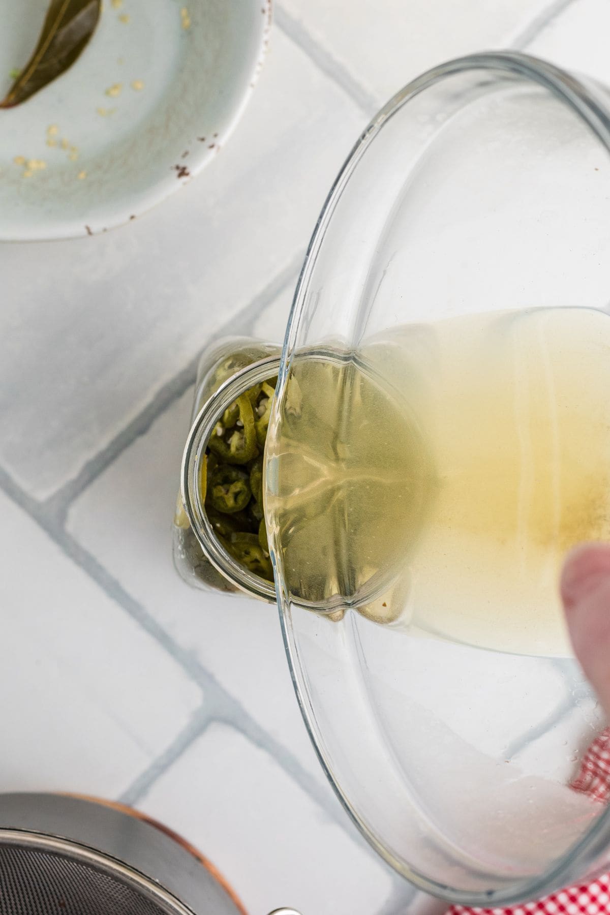 Pouring additional brine into the jar with the jalapenos.