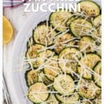 Sliced pan fried zucchini with grated Parmesan and lemon on a white plate viewed from above.