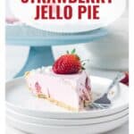 Slice of strawberry jello pie with a fresh strawberry on top, on a plate with a fork, lanas cooking website.