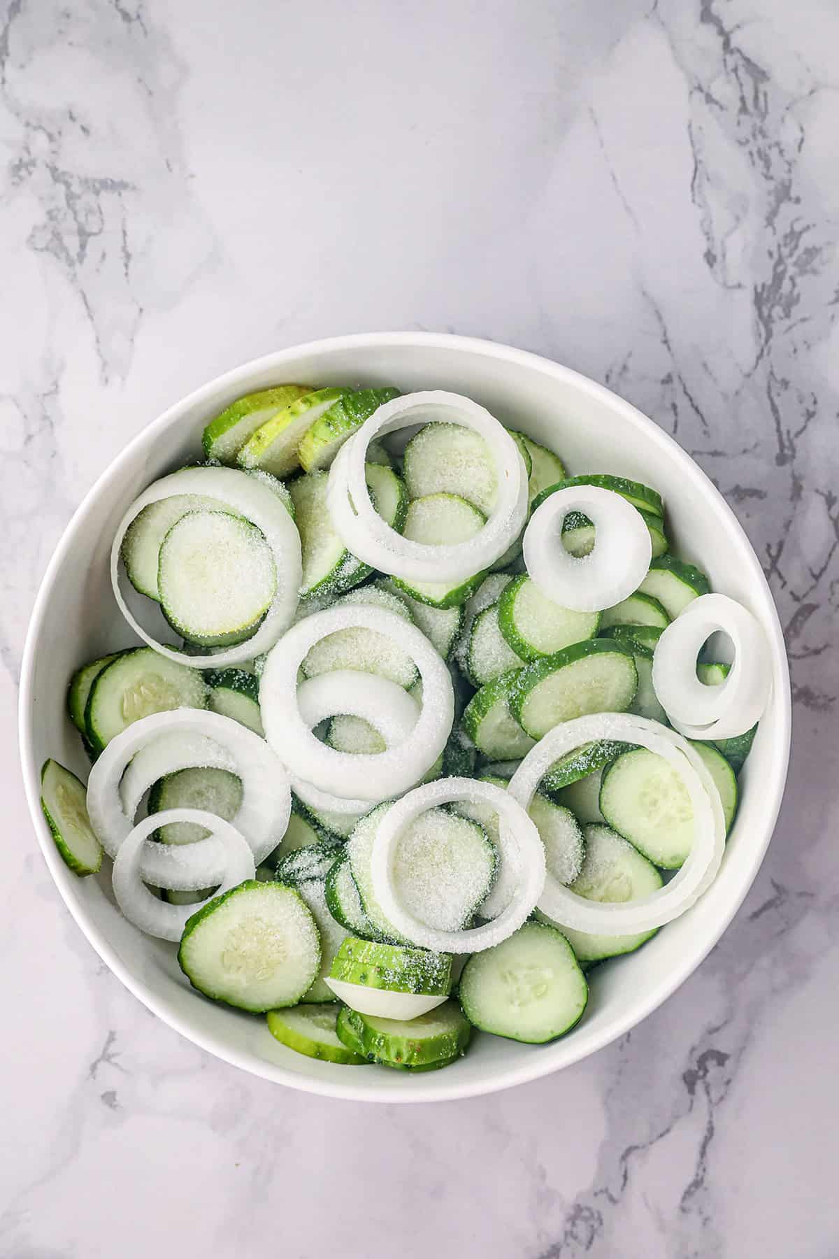 Cucumbers and onions in a bowl with salt.