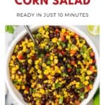 Bowl of black bean and corn salad with diced veggies and a spoon, ready to serve.