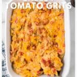 Baked cheesy tomato grits in a white dish with a spoon, on a blue and white towel.