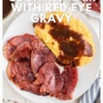 A plate of country ham and yellow grits topped with red eye gravy, shown from above on a white table.