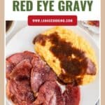 Plate with slices of country ham and yellow grits topped with red eye gravy, viewed from above.