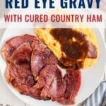 A white plate with slices of cured country ham, creamy cheese grits topped with brown red eye gravy. Part of a biscuit and an overhead view of a gravy bowl are visible. Text reads: “Red Eye Gravy with Cured Country Ham.”.
