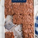 Overhead view of a chocolate Texas sheet cake, partially sliced, with a spatula on a baking sheet.