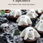 Chocolate cupcakes topped with white ghost-shaped icing, decorated with small skulls and gravestones.