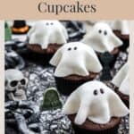 Chocolate cupcakes topped with white fondant ghosts, decorated with a skull, tombstones, and chains.