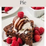 A slice of chocolate fudge pie topped with vanilla ice cream, chocolate sauce, and fresh raspberries.