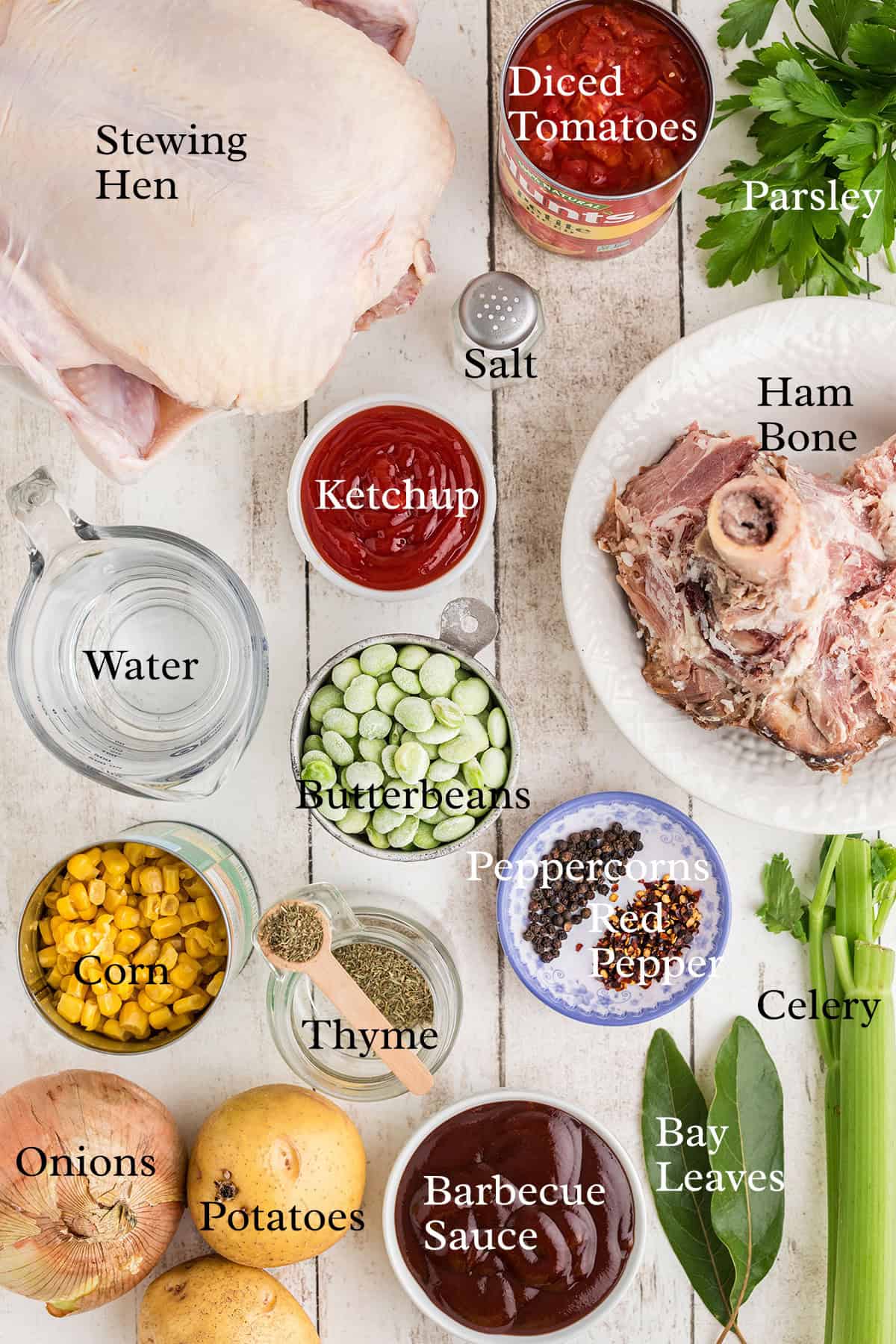 Ingredients for stew labeled on a table, including chicken, ham bone, vegetables, sauces, and seasonings.