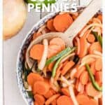 Bowl of sliced carrots, onions, and green peppers with a wooden spoon beside an onion on a wooden table.