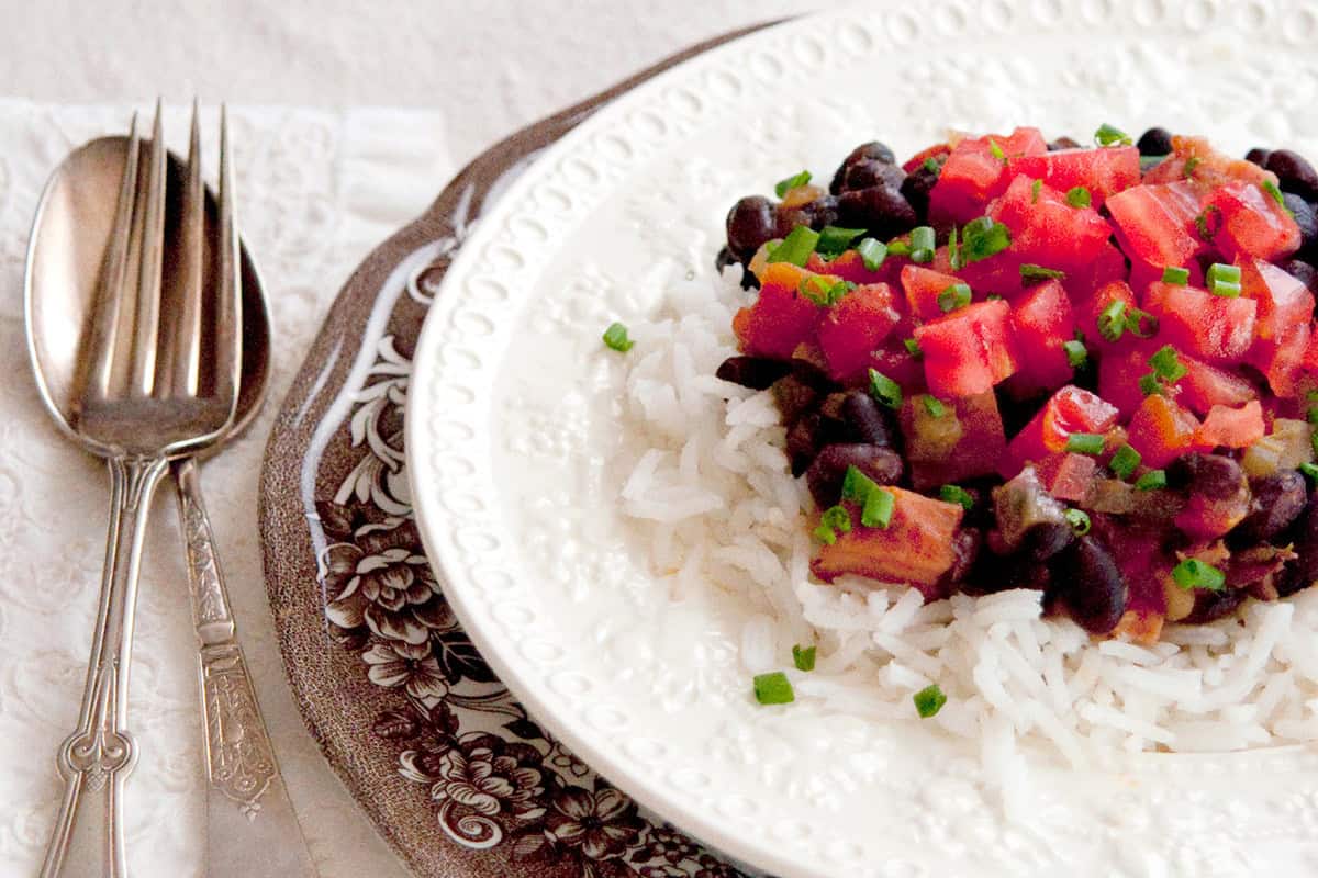 Black beans and rice with tomato garnish on a white plate.