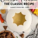 Overhead view of cheese fondue pot surrounded by bread, chips, and vegetables for dipping.