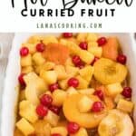 A white dish filled with baked mixed fruit, including pineapple, cherries, and apricots.