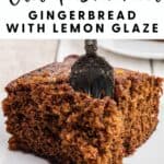 A fork in a slice of old-fashioned gingerbread cake with lemon glaze on a white plate.