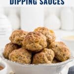 A bowl of sausage balls with dipping sauces, displayed on a white rustic table.