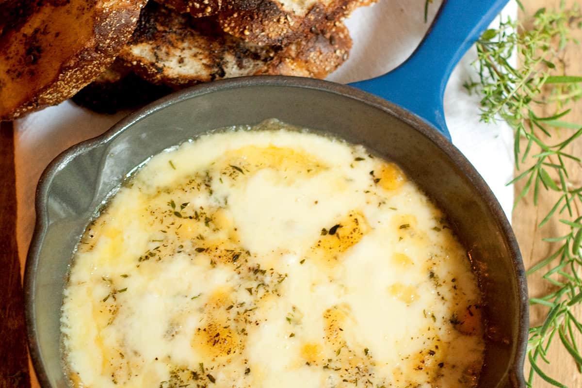 Baked fontina in a small skillet with toasted bread on the side.