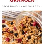 Jar of homemade granola with oats and dried berries spilling onto a surface, beside a striped towel.