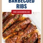 Barbecued ribs on a white platter, garnished with herbs, with text Slow Cooker Barbecued Ribs.