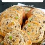A silver tray filled with cheesy mushroom pinwheels, garnished with chopped green onions.