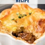Golden beef and stout pie with flaky pastry crust in a white dish, topped with herbs.