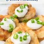 Four potato pancakes topped with sour cream and chopped green onions on a white plate.