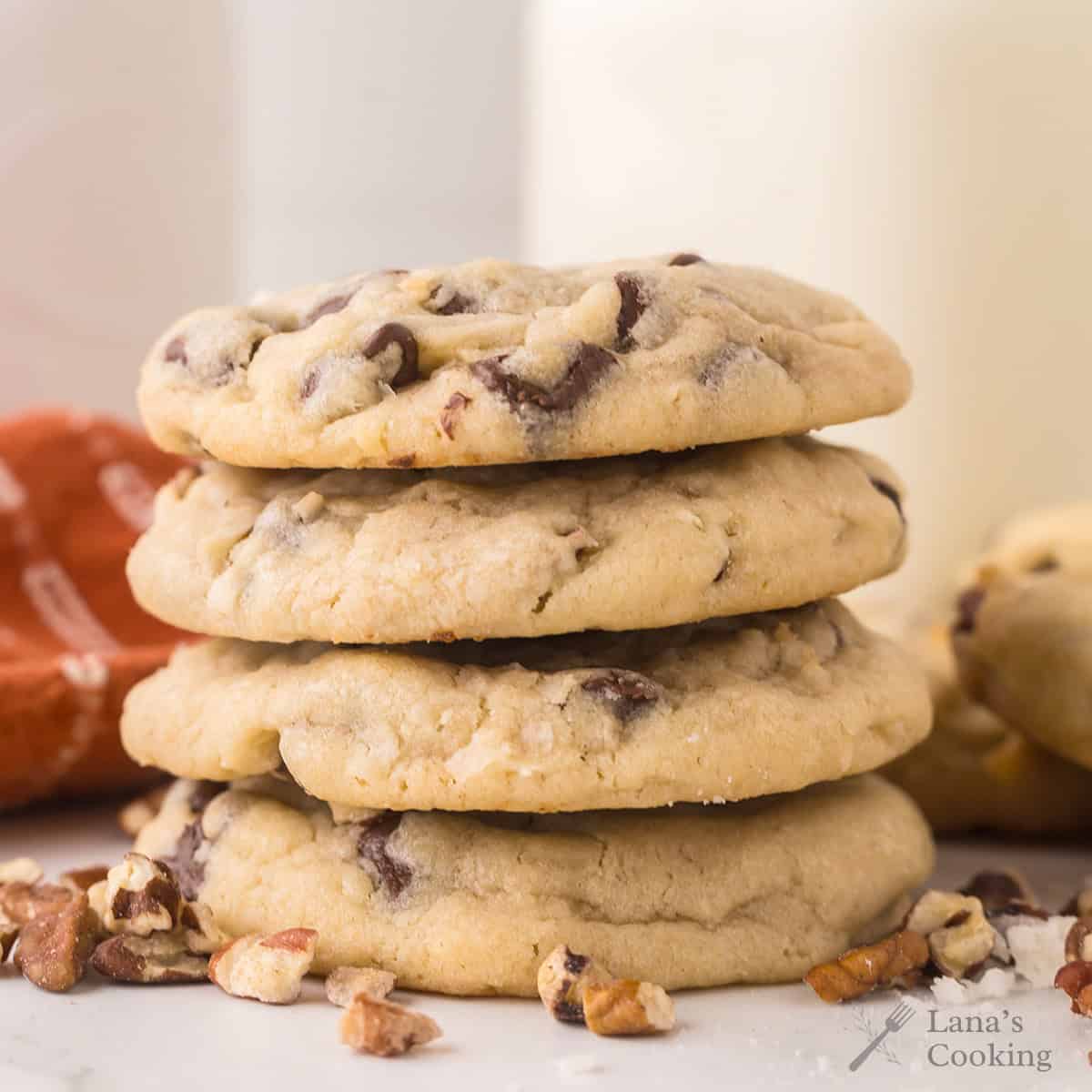 A stack of four cookies surrounded by pecans and coconut.