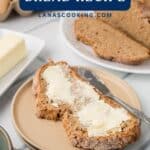 A slice of Irish brown soda bread with butter on a plate, with more bread and butter in the background.