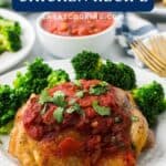 Baked chicken topped with salsa and parsley, served with broccoli on a white plate, salsa bowl in background.