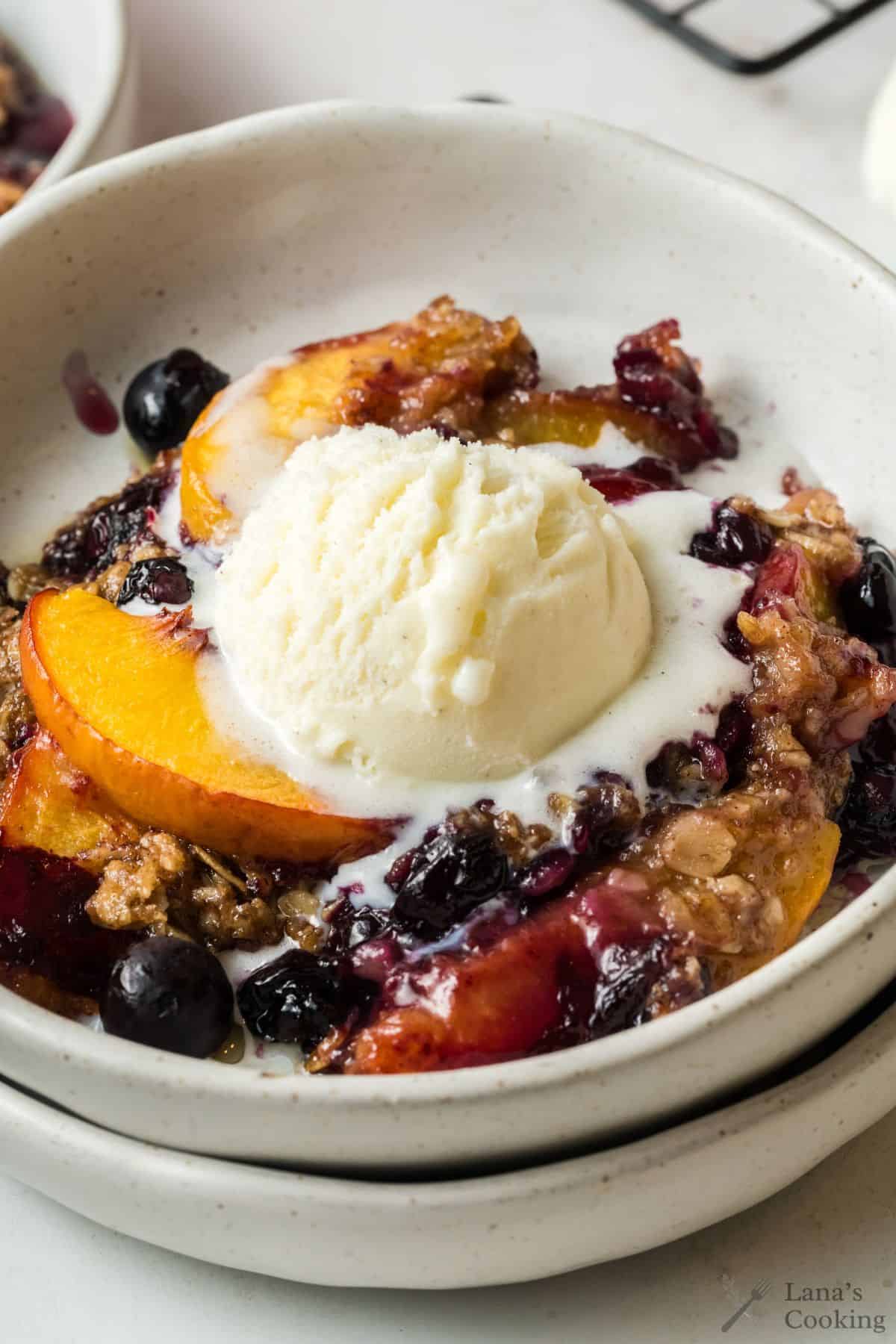 Baked blueberry peach crisp in a large white bowl.