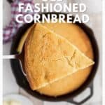 A slice of golden cornbread is held above a cast iron skillet filled with more cornbread.
