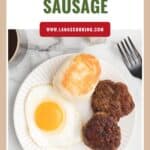 A plate with a fried egg, biscuit, and two sausage patties next to a cup of coffee and a fork.