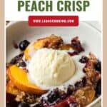 A bowl of blueberry peach crisp topped with a scoop of melting vanilla ice cream.