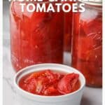 Glass jars and a white bowl filled with home-canned tomatoes on a marble countertop.