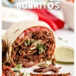A close-up of a machaca burrito cut in half, filled with shredded beef, veggies, and served with lime.
