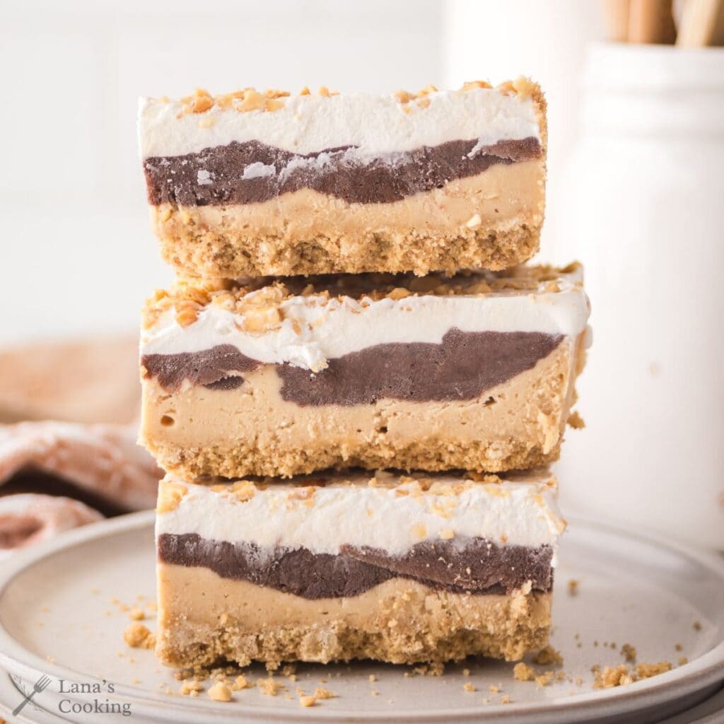 Peanut butter delight slices stacked on top of each other with layers clearly visible.