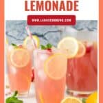 Glasses of pink lemonade with lemon slices, strawberries, and mint, with a pitcher in the background.